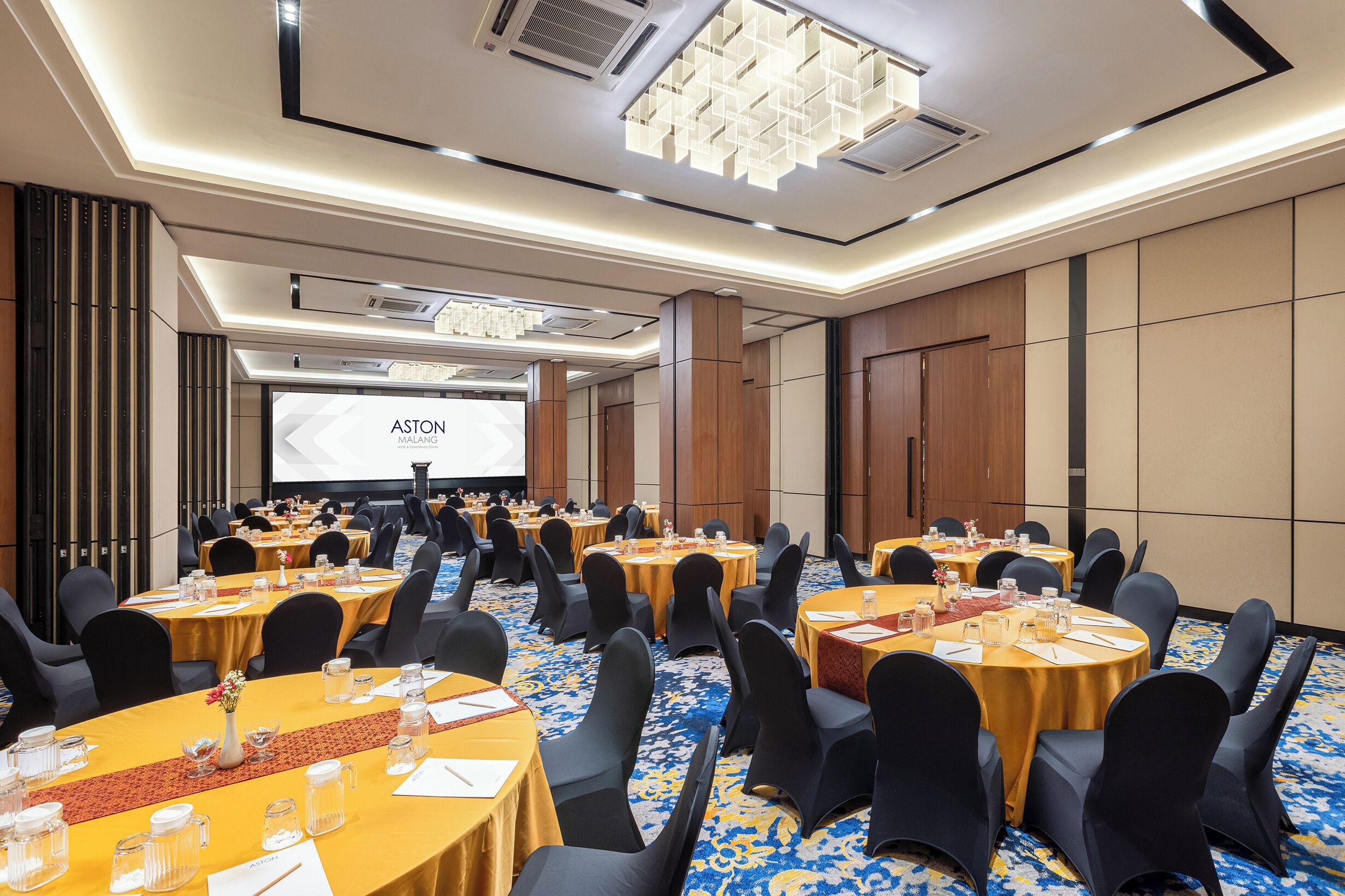 A conference room with multiple tables, chairs, and a projector screen.