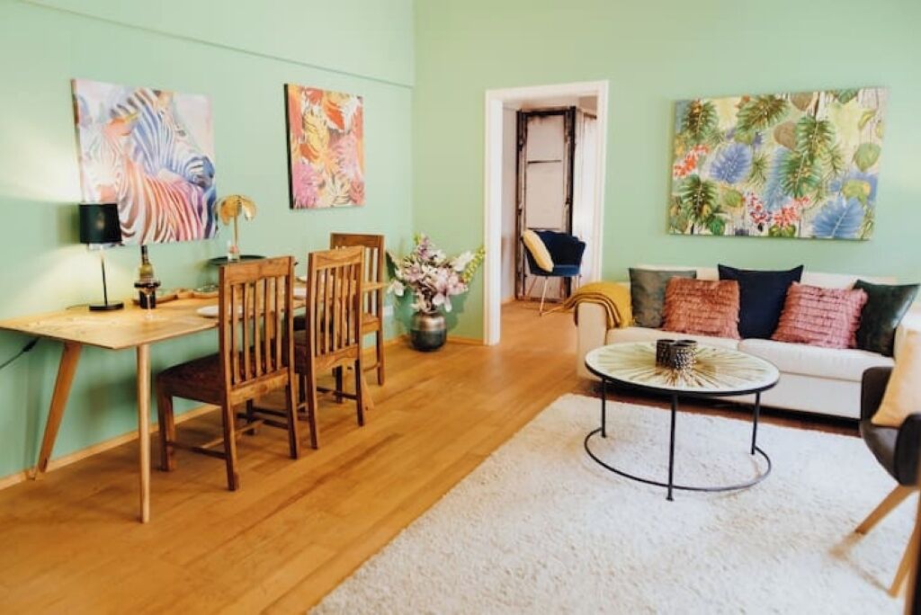Ein Wohnzimmer mit Essbereich, ausgestattet mit Holzmöbeln, einem weißen Sofa und Kunstwerken an den Wänden.