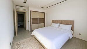Ein modernes Schlafzimmer mit einem großen Bett, einem Holz-Kopfteil und einem begehbaren Kleiderschrank mit Schiebetüren.