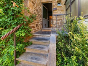 Un escalier en pierre mène à une porte sur laquelle est affiché un panneau indiquant : « Bienvenue ».