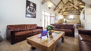 Un salón amplio con dos sofás de cuero marrón, una mesa de centro de madera y un ventanal grande.