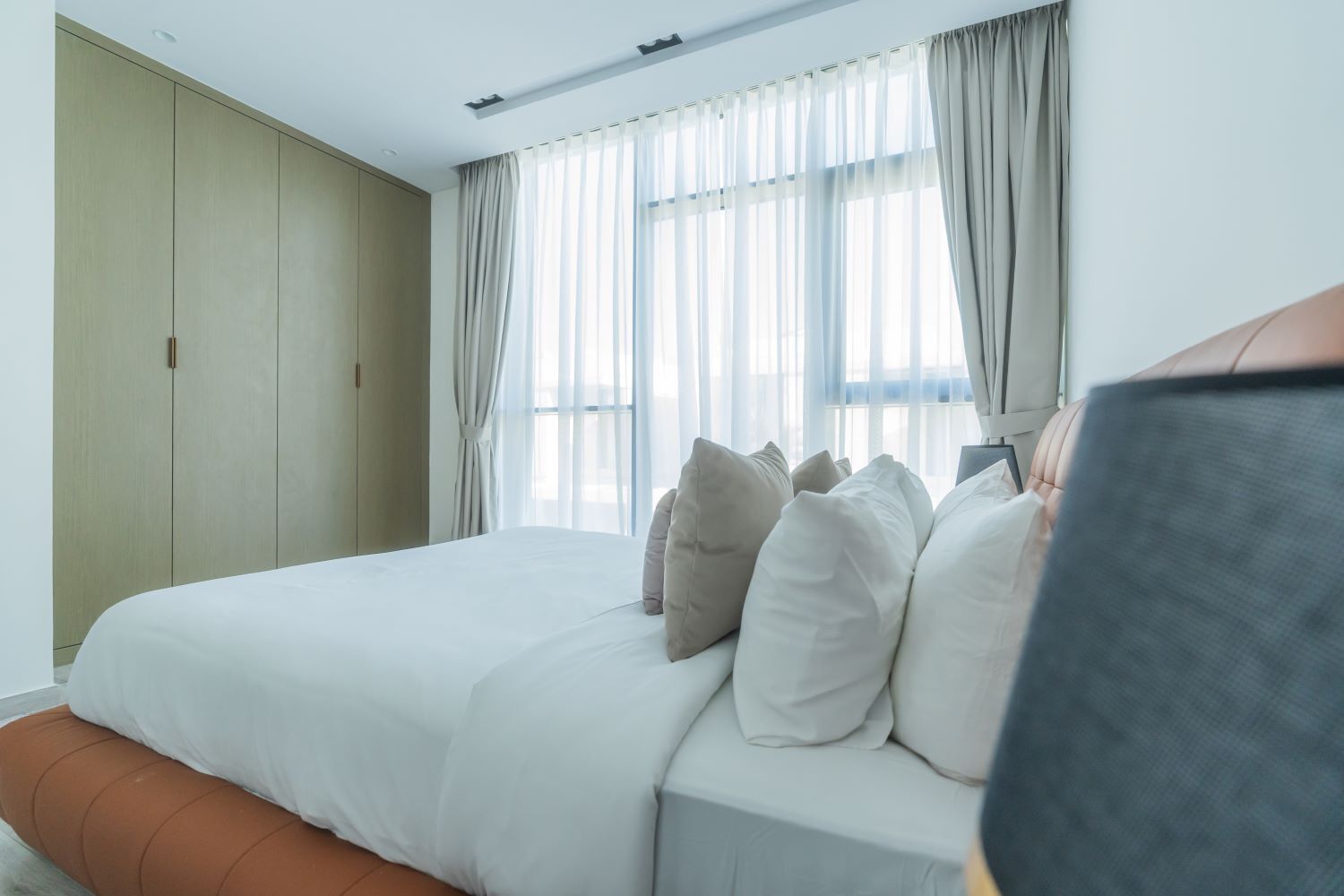 A hotel room with a large bed, a wardrobe, and a window with curtains.