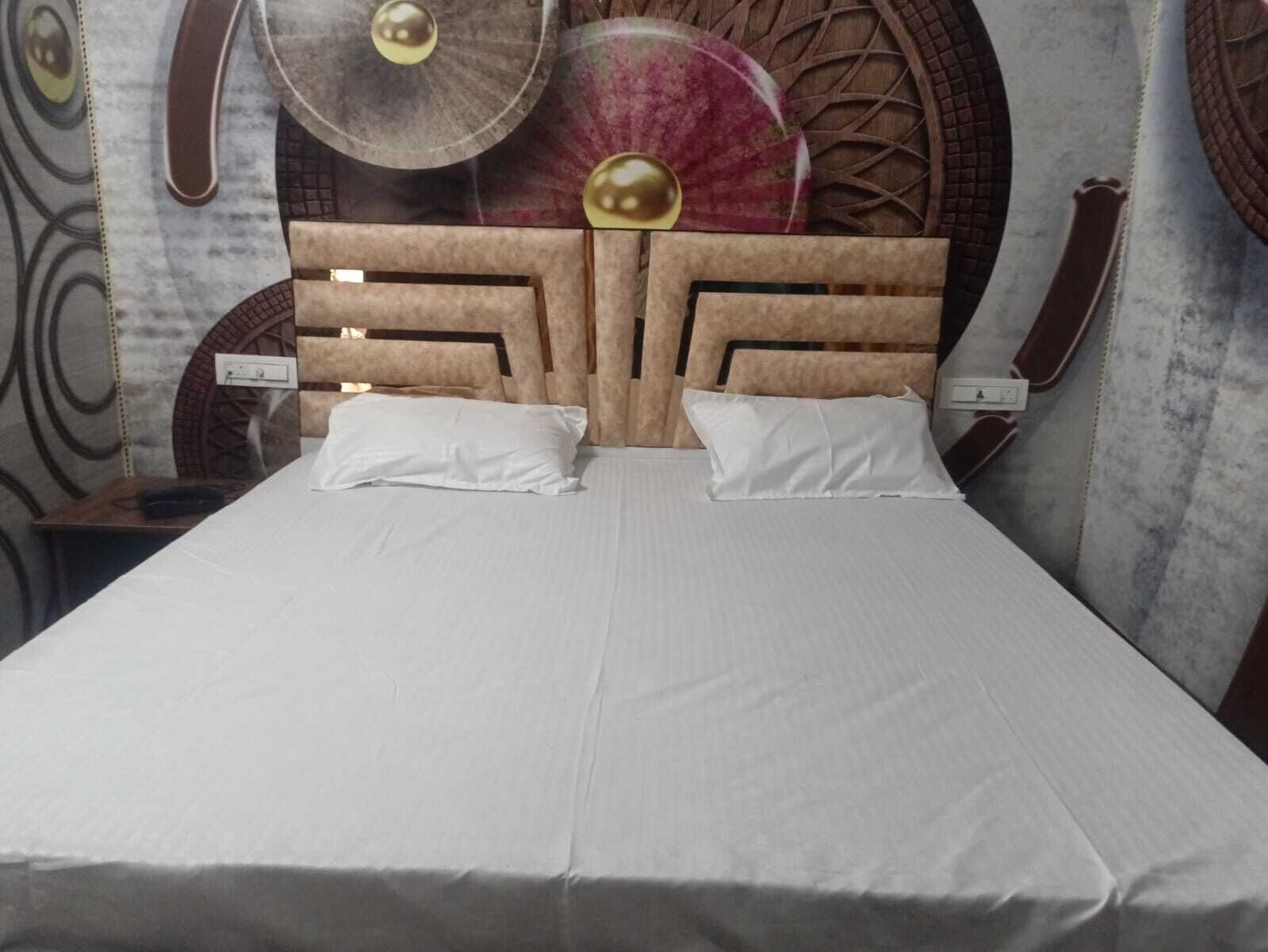 Una cama con cabecera de madera, dos almohadas blancas y una colcha blanca.