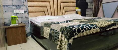 A bedroom with a bed, a wooden nightstand, a green water bottle, and a brick wall.