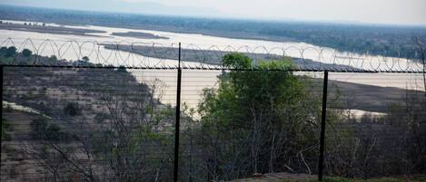 A fenced area with a view of a river and distant mountains.