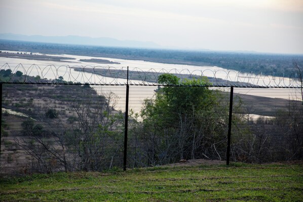 A fenced area with a view of a river and distant mountains. - Chirundu Haven (Chirundu)