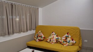 A living room with a yellow sofa, white coffee table, and a window with curtains. - Bed&Bike (Aulla)