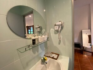 A bathroom with a glass shelf holding toiletries, a sink with a flower, and a hairdryer mounted on the wall. - Samma Karuna Resort - Intoxicants free (Ko Pha-ngan)