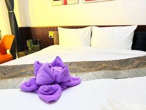 A hotel room with a neatly made bed, a wooden headboard, and a purple towel on the bed. - Samma Karuna Resort - Intoxicants free (Ko Pha-ngan)