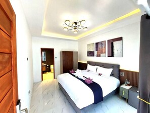 A modern bedroom with a large bed, bedside tables, a ceiling light, and artwork on the wall. - Samma Karuna Resort - Intoxicants free (Ko Pha-ngan)