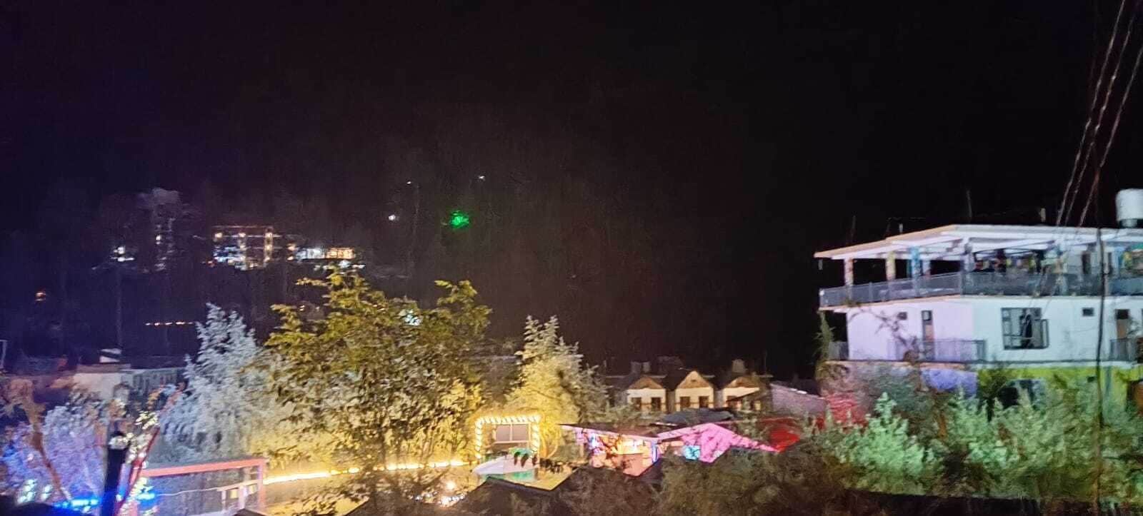 Vista noturna de um bairro residencial com casas e um edifício grande com varanda.