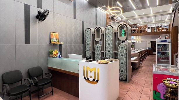 Un espace d’accueil au design moderne, comprenant un comptoir de réception, un coin salon et un mur décoratif agrémenté de panneaux à motifs.