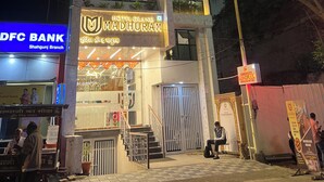 Un hôtel appelé « Hotel Grand Madhuram », doté d’une façade moderne, d’une entrée bien visible et d’un escalier menant à l’entrée.