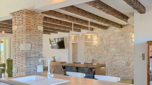 A modern kitchen with a large island, stone accents, and exposed wooden beams. - Spacious Country Villa With Private Pool (Tar-Vabriga)