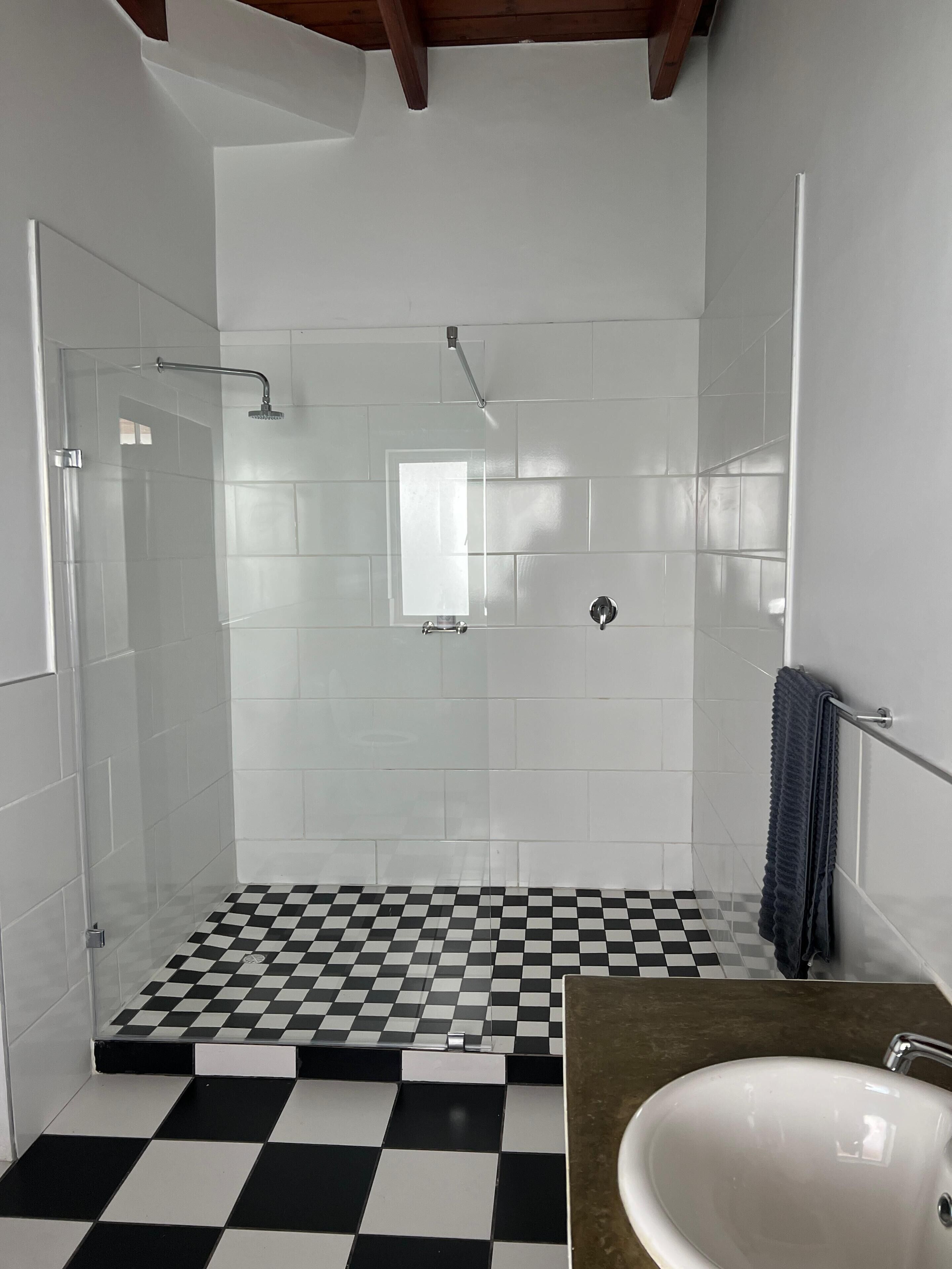 A bathroom with a checkered floor, a shower, and a sink.