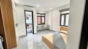 Un dormitorio moderno con cama, una mesita con sillas y un ventanal con barrotes.