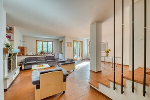 A spacious living area with a sofa set, a coffee table, and a staircase leading to an upper level.