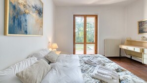 Ein Schlafzimmer mit einem Bett, einem Schreibtisch, einem Heizkörper und einem großen Fenster.