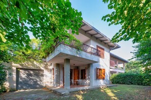 Una casa de dos pisos con balcón, un porche cubierto y garaje.