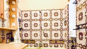 Une cuisine de taille réduite, avec des carreaux décoratifs, un lave-linge et des placards en bois.