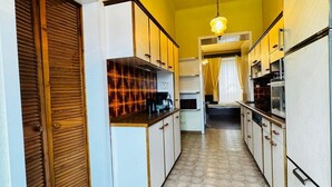 Une cuisine étroite avec des meubles blancs, une porte en bois et un sol à motifs hexagonaux.