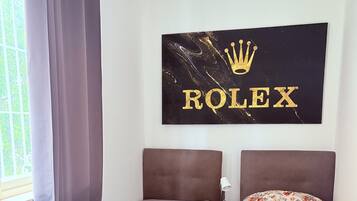 Ein Schlafzimmer mit einem Bett, einem Nachttisch, einem Wandbild und einem Fenster mit Vorhängen.