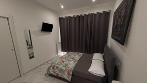A modern bedroom with a bed, a flat-screen TV, a radiator, and a shower. - Villa Life  (San Donato Milanese)
