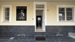 A building entrance with a black and white poster, barred windows, and a tiled floor. - Villa Life  (San Donato Milanese)