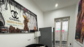A modern living room with a black sofa, a chandelier, and a large mural on the wall. - Villa Life  (San Donato Milanese)