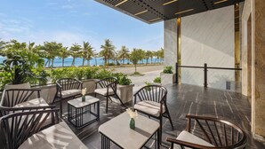 Un espace extérieur aménagé avec des meubles modernes, offrant une vue sur la plage et doté d’un grand mur en marbre.