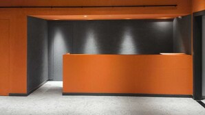 A reception area with a modern design, featuring a large, circular light fixture and a reception desk with a black and orange color scheme. - D Capstone (Batam)