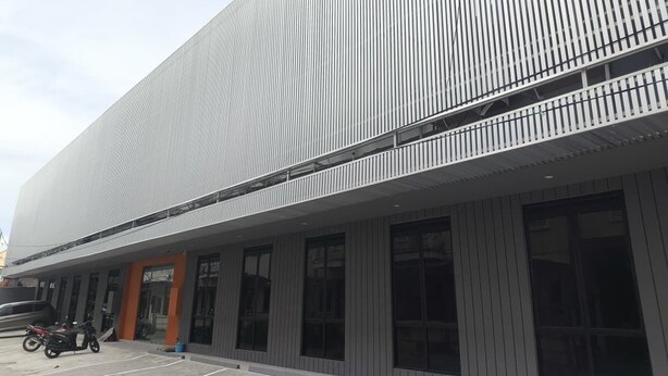 A modern building with a flat facade, large windows, and a parking area with motorcycles. - D Capstone (Batam)