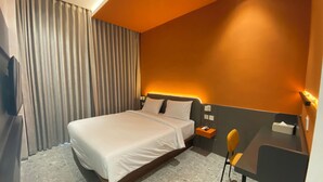 A modern hotel room with a large bed, a desk, and a chair. - D Capstone (Batam)