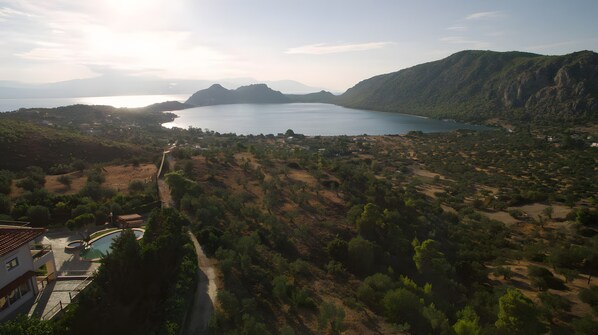 Paisaje costero con piscina, carretera y vistas al mar y a las montañas.
