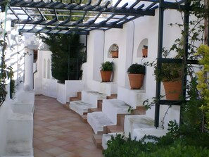 Una escalera exterior cubierta con paredes blancas y escalones de terracota que conducen a un nivel superior.
