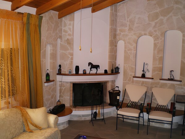 Une pièce aux murs de pierre, avec une cheminée, un canapé et deux fauteuils.