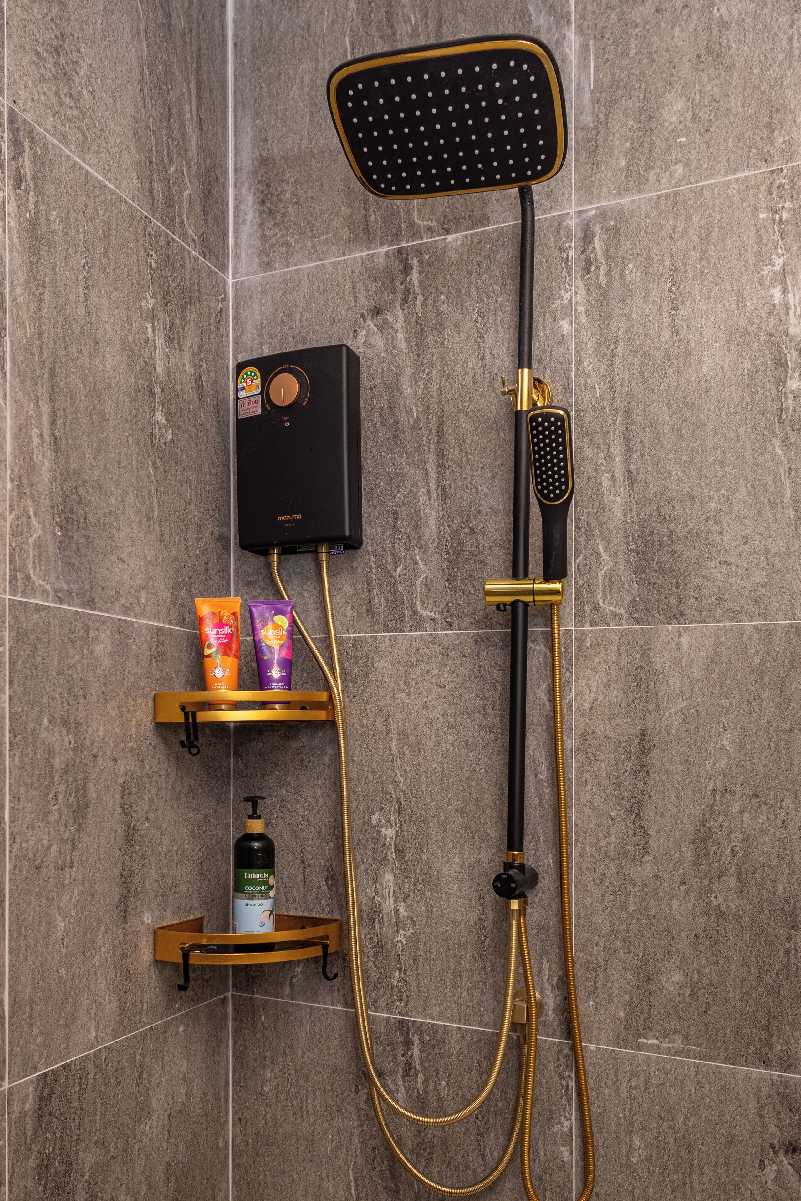 A shower with a handheld showerhead, a wall-mounted control panel, and two shelves with toiletries.