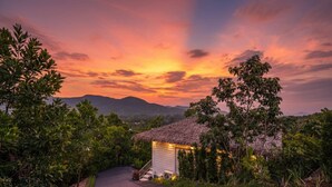 A house with a thatched roof, surrounded by lush greenery and a wooden pathway leading to it. - Archies Paradise View (Ko Pha-ngan)