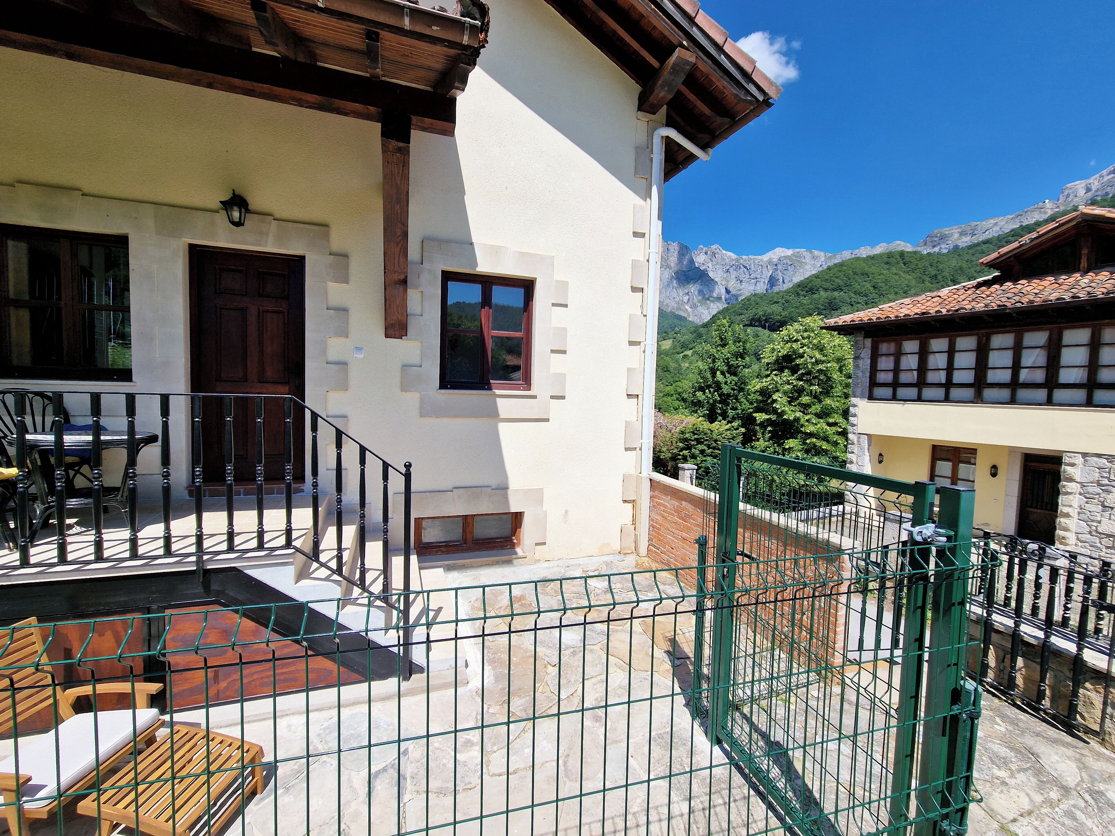 A two-story building with a balcony, a stone staircase, and a view of mountains.