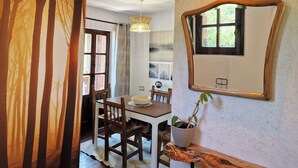 Un comedor con mesa de madera, sillas y una planta en maceta.
