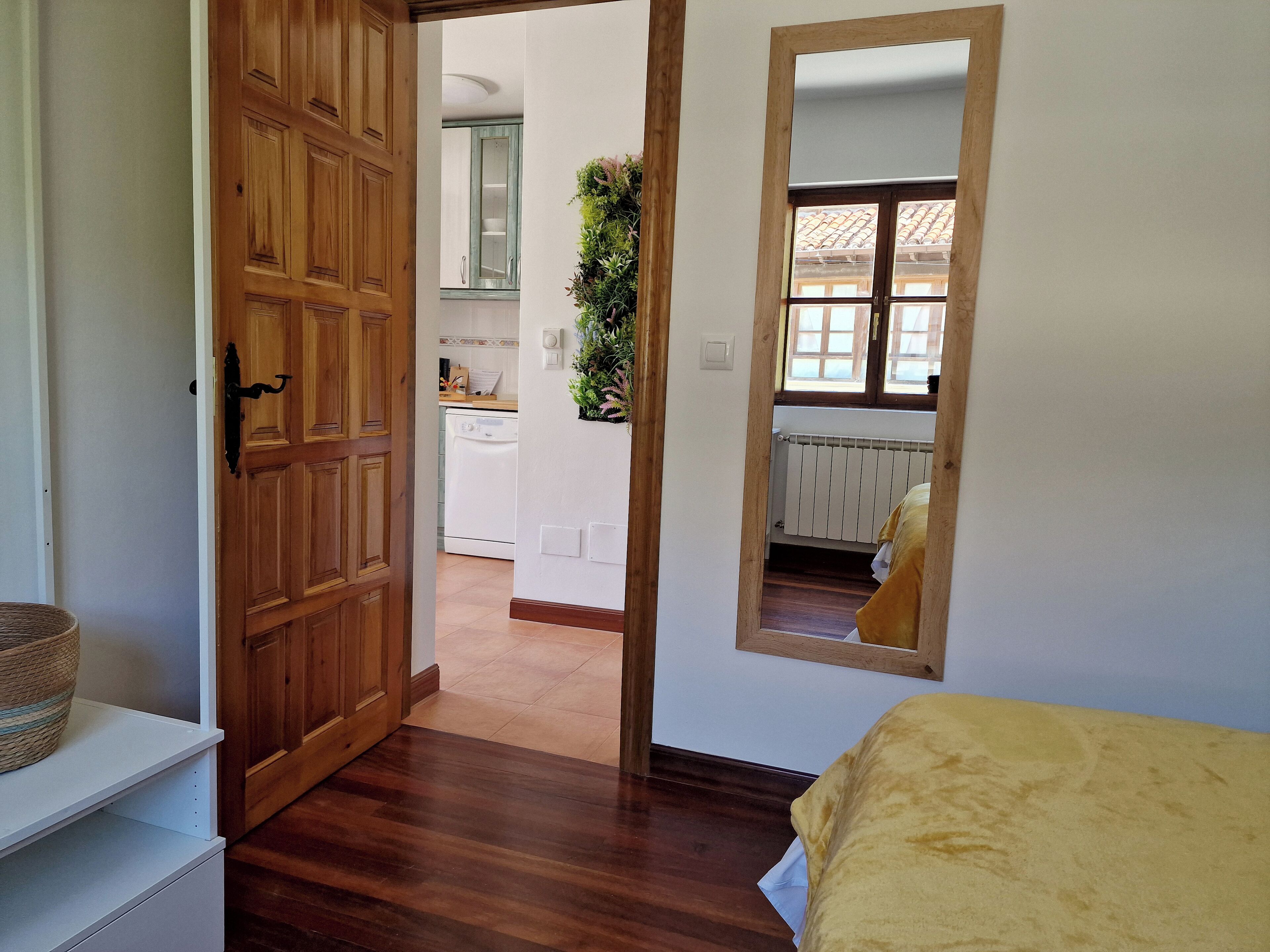 Ein Schlafzimmer mit Holztür, Spiegel und einem Bett mit gelber Decke.