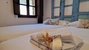 Una cama bien hecha con toallas dobladas y una etiqueta, una ventana con vistas, y una ventana con marco azul.