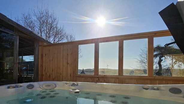 Un jacuzzi con vistas despejadas al cielo y el sol brillando a través de las ventanas.