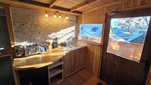 Una cocina de madera con salpicadero de azulejos, un lavabo y una ventana con vistas a una azotea.