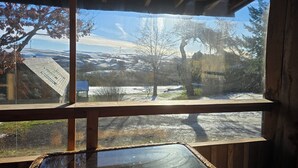Una cabaña de madera con un ventanal grande que da a un paisaje nevado.