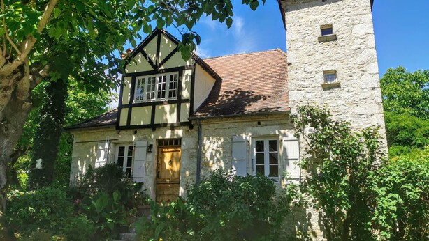A traditional two-story house with a stone tower, surrounded by lush greenery. - The Farmhouse (MEYRONNE)
