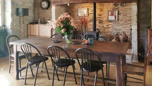 A rustic dining room with a stone wall, wooden table, and chairs. - The Farmhouse (MEYRONNE)