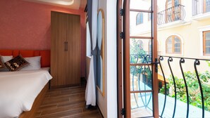 A bedroom with a bed, a wooden wardrobe, a window with a view of a balcony and building. - Sóng and Sun Phu Quoc Hotel (Phu Quoc)