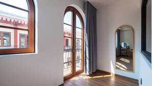 A room with a large arched window, a door leading to an outdoor balcony, and a mirror on the wall. - Sóng and Sun Phu Quoc Hotel (Phu Quoc)