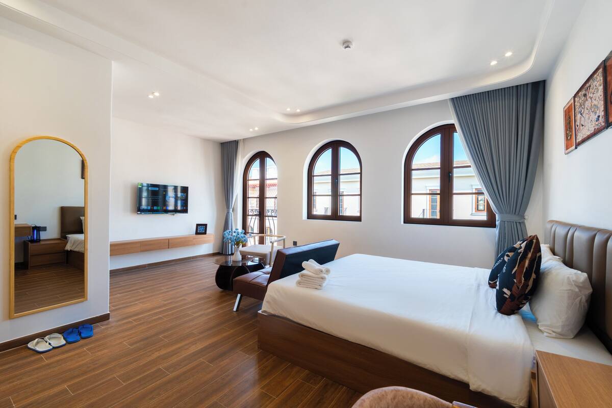A modern hotel room with a large bed, a desk, a chair, and a television.